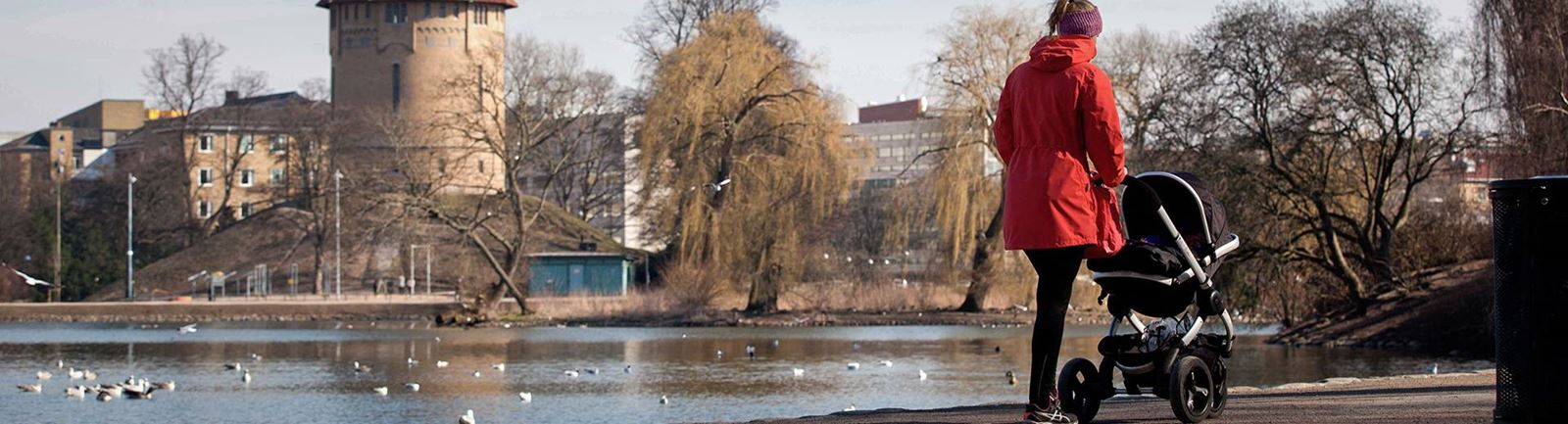 Kvinna med barnvagn går i Pildammarna i Malmö en höstdag