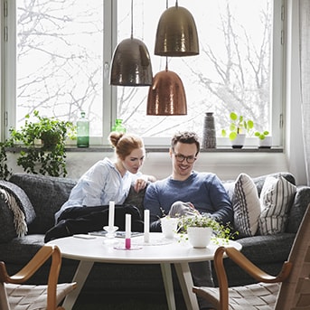 Kvinna och man sitter i en soffa och tittar på mobilen